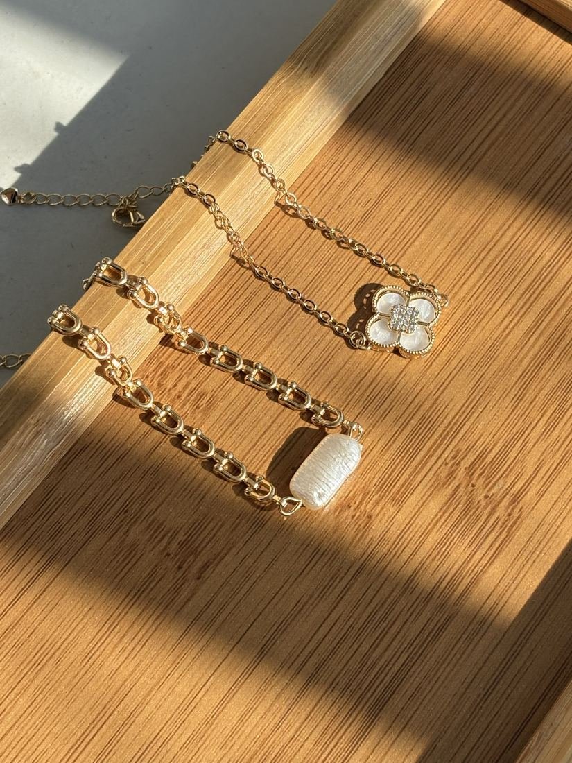 Pulseiras douradas com flor e pérola sobre bandeja de madeira