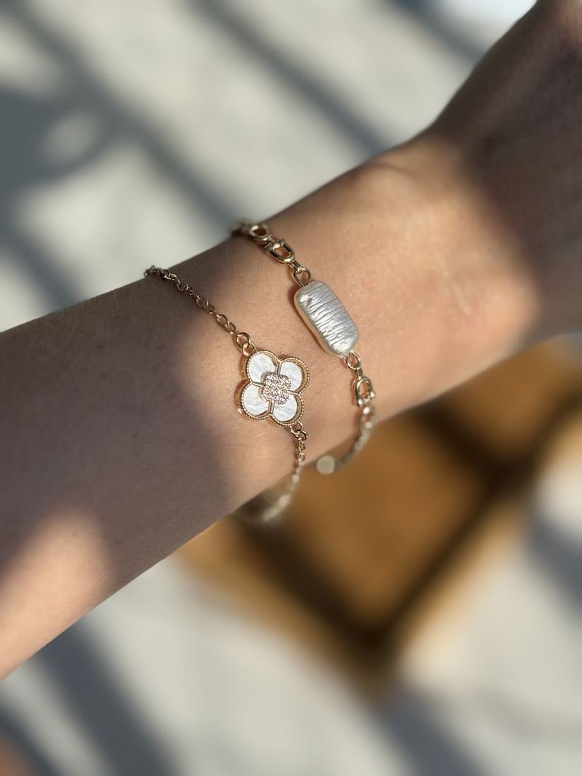 Pulseiras douradas com pingente de flor e pérola no pulso
